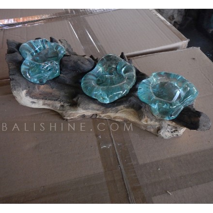 Balishine: Your natural source of indonesian handicraft presents in its Home Decor collection the Blown Glass Candle Holder Triple on Teak Wood Stand:13INT168059:Unique mouth blown slumped glass triple candle holder crafted by talented glass artisans on the island of Bali. Recycled molten?glass is?slumped over the top of a reclaimed teak root base. This forms a unique glass scape as the molten glass drapes & flows and takes on the?gnarly?shape of the wood, so beautiful, almost looks like water droplets nestled in the crevices?of the wood.?   Because each item is handmade, shape and size can vary slightly and tiny bubbles may appear within the glass. This exemplifies the hand-blown technique, making every piece a unique example of blown glass craftsmanship.